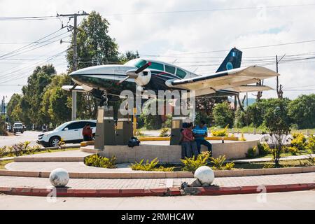 a Piper Aztec mounted on a traffic roundabout as a monument at the entrance to Cobán Airport, Guatemala Stock Photo