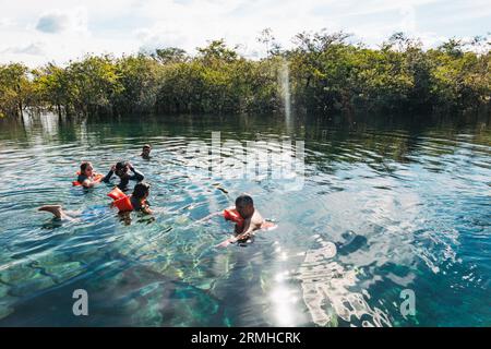 a family swim in the crystal clear waters of Crater Azul (the Blue Crater) in northern Guatemala Stock Photo