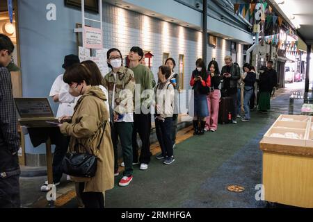 Japan, Fukuoka, Hakata. Yanagibashi Market. Chinese and Korean Patrons Waiting for Seating in a Popular Restaurant. Stock Photo
