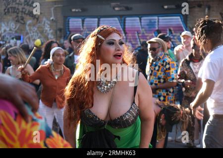 Woman with red hair dances as people play drums on Portobello Road during the Notting Hill Carnival. 28/08/2023 Stock Photo