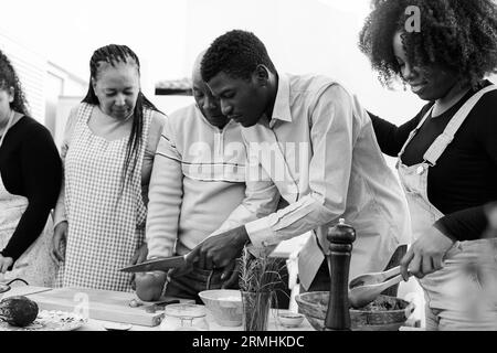 Outdoor kitchen: African family cooking vegetarian food at home patio - Father, mother, daughter, brother making healthy food dinner - Soft focus on r Stock Photo