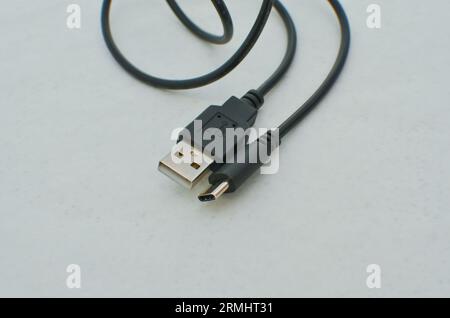 Black USB Type-C cable detail highlighted on a clear surface, perfect for modern technology concepts. Close-up black USB Type-C cable providing speed Stock Photo