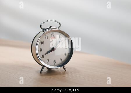 old mechanical alarm clock on wooden table in a living room. Stock Photo