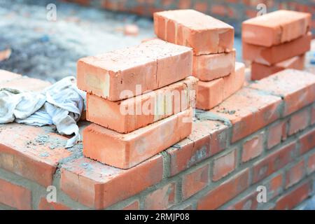Brick house wall constuction with stack of red bricks. Building house brick wall concept. Stock Photo