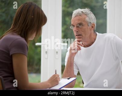 Close up of young woman taking notes from consultation with gray haired man Stock Photo