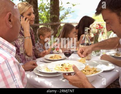 Extended family sitting at table having pasta meal Stock Photo
