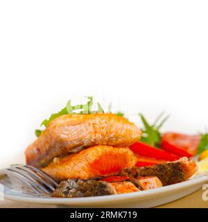 Grilled fresh samon filet with vegetables salad tomato arugula mushroomsand paprika on top Stock Photo