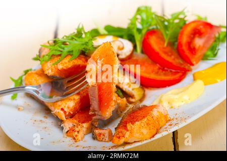 Grilled fresh samon filet with vegetables salad tomato arugula mushroomsand paprika on top Stock Photo