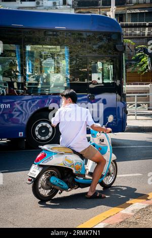 A young Thai man speeds along Krung Kasem Rd. near Hua Lamphong train station on his vespa moped, Bangkok, Thailand. Stock Photo