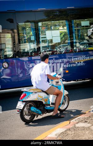 A young Thai man speeds along Krung Kasem Rd. near Hua Lamphong train station on his vespa moped, Bangkok, Thailand. Stock Photo