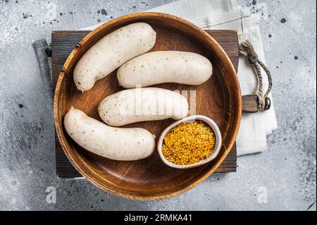 Bavarian white sausage in wooden plate with mustard. Gray background. Top view. Stock Photo