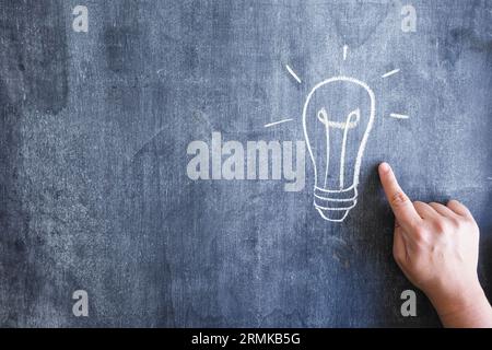 Close up person pointing finger hand drawn light bulb chalkboard Stock Photo