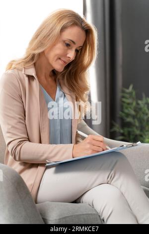 Mid shot woman therapist writing clipboard Stock Photo