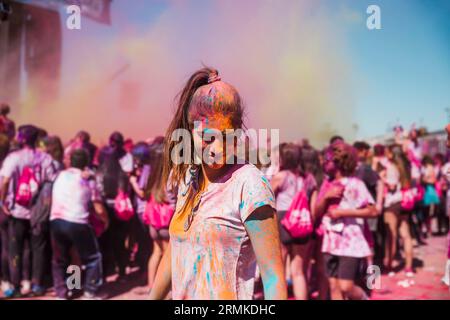 Young woman enjoying with holi color crowd Stock Photo