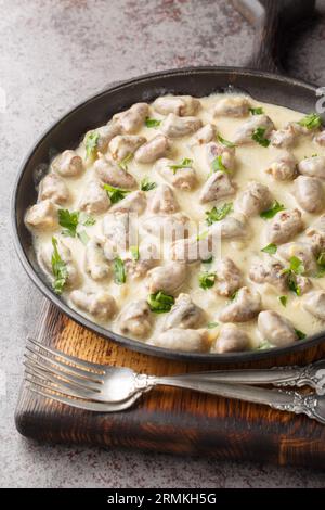 Delicious chicken hearts in garlic cream sauce close-up in a plate on the table. Vertical Stock Photo