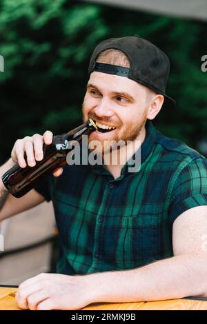 Man opening beer bottle cap with his teeth Stock Photo