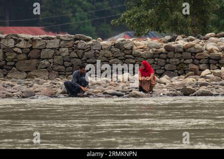 August 25, 2023, Keran, Jammu and Kashmir, India: Man and woman in Pakistan administered Kashmir resting on the banks of Neelam river or Kishan Ganga which acts as a line of control between nuclear-armed neighbours India and Pakistan, at Keran village in Kupwara district, some 150km north Srinagar. The highly restricted border area was a battle field and used to witness intense shelling and gunfire, now a most attractive tourist hotspot after the 2021 ceasefire pact between the armies of India and Pakistan. (Credit Image: © Faisal Bashir/Pacific Press via ZUMA Press Wire) EDITORIAL USAGE ONLY! Stock Photo