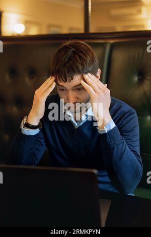 Thoughtful businessman working on new online project on laptop computer sitting at the table in cafe. Instant workplace. Stock Photo