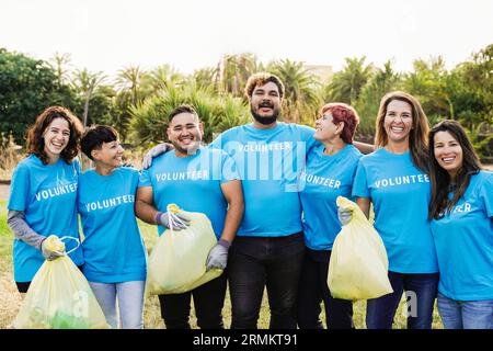 Happy volunteers helping community clean and recycle plastic at nature park city - People from different ages and ethnicity work together for environm Stock Photo