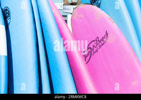 Colourful surfboards stacked and available to hire at the surf hire shop at Fistral Beach in Newquay in Cornwall in England in the UK. Stock Photo