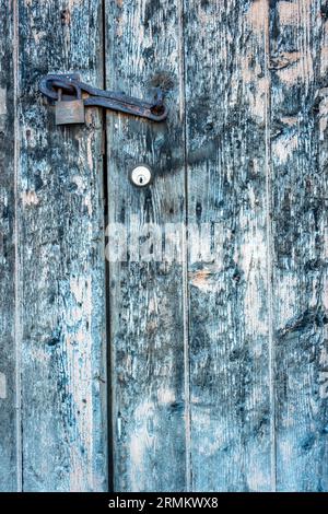 A close up of a lock and padlock on an old weathered door, cool tones, vertical Stock Photo