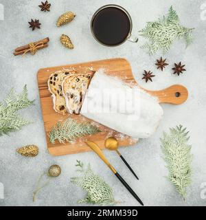 Christmas composition with tasty stollen cake on a wooden board, cutlery and coffee cup on gray table Stock Photo