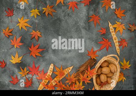 Frame made of fall maple leaves, walnuts on dark background. Autumnal concept. Flat lay, top view Stock Photo