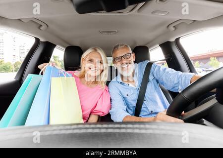 Cheerful pensioners driving home after shopping in mall, talking, smiling Stock Photo