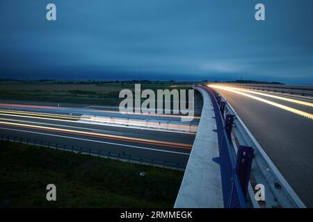 Road overpass over multiple lane highway in countryside at twilight. Themes car transportation, direction and connection. Stock Photo