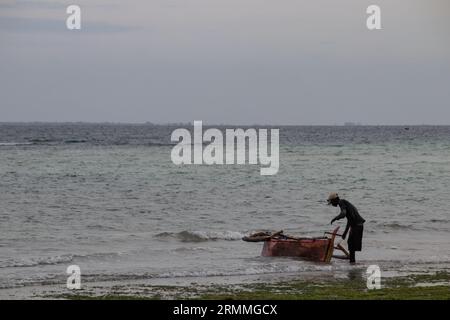Lonely fisherman at the Mozambique sandy beach preparing boat to go for sailing and fishing Stock Photo