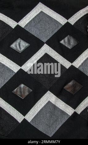 Detailed inserts in black genuine leather on a knitted woolen background with an abstract pattern. Abstract fabric texture. Stock Photo