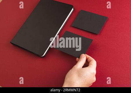 Black notebook and caucasian woman holding black paper card on red background Stock Photo