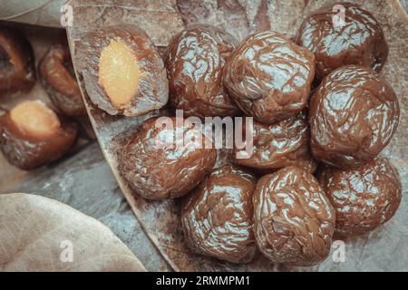 Close-up of Flavored preserved chinese plums (Preserved fruits) on wooden background. Its flavour has sour, salty and sweet taste. Space for text, Sel Stock Photo