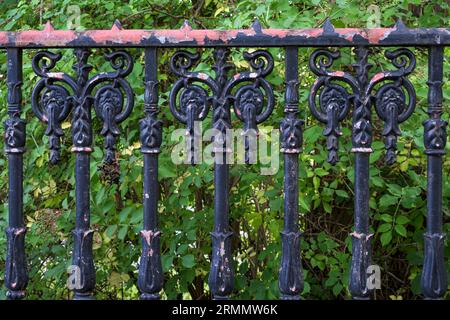 An old distressed ornamental cast iron metal fence on a city street Stock Photo