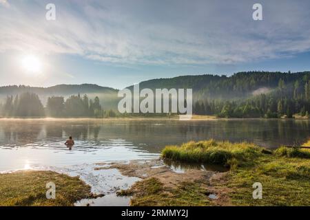 Tamsweg: morning mist on lake Prebersee, bather in Lungau, Salzburg, Austria Stock Photo
