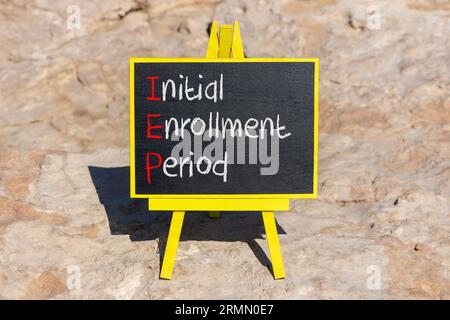 IEP symbol. Concept words IEP Initial enrollment period on beautiful black chalk blackboard. Beautiful stone beach background. Medical and IEP Initial Stock Photo