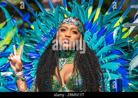 Female participant at the Notting Hill Carnival Grand Parade 2023, London, UK. Person of colour wearing bright, colourful feather plumage costume Stock Photo