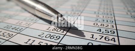 A gray metal pen lies on a table with numbers, close-up Stock Photo