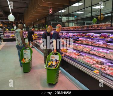 Men compare the prices of meat, in the butcher section of a large supermarket in Rome, Italy Stock Photo