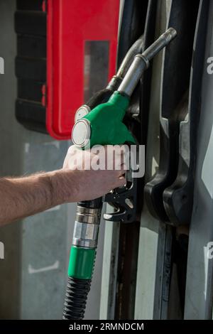 Close-up of a caucasian man's hand releasing the petrol pump after refueling. Vertical image. Stock Photo