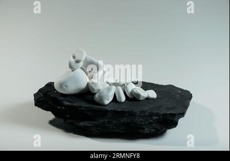 white smooth stones randomly lie over one black flat stone Stock Photo