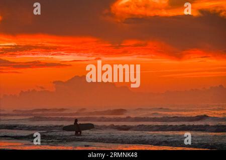 Isle Of Palms, United States. 29th Aug, 2023. A surfer silhouetted by the dramatic sunrise checks the wave conditions caused by the passing Hurricane Franklin before heading out, August 29, 2023 in Isle of Palms, South Carolina. Hurricane Franklin, a Category 4 monster storm is heading to Bermuda while Hurricane Idalia is expected to pass overhead on Thursday. Credit: Richard Ellis/Richard Ellis/Alamy Live News Stock Photo