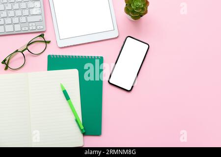 Keyboard with gadgets, eyeglasses and stationery on pink background Stock Photo