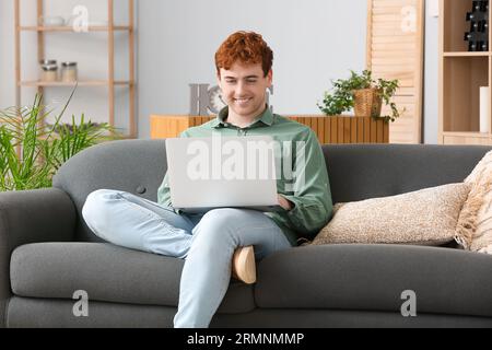 Male freelancer working with laptop on sofa at home Stock Photo