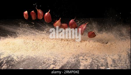 Garlic, allium savitum, Garlic pawns Falling on Garlic Powder on Black ...