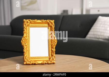Beautiful golden vintage frame on wooden coffee table indoors, space for text Stock Photo