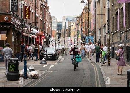 People walking and cycling along Brick Lane - a famous street in the East End of London and the heart of the country's Bangladeshi community. UK Stock Photo