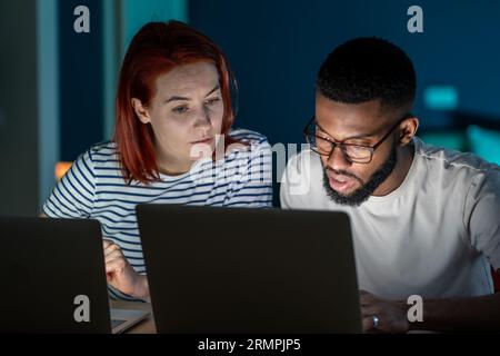 Family wife husband doing life routine on laptops at home in evening advising discussing together. Stock Photo