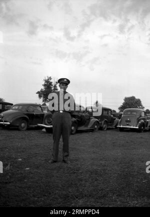 Solider in uniform standing near cars during 1940s. Members of the United States Army’s 114th infantry division train to fight against Germany in Europe during WWII. Stock Photo