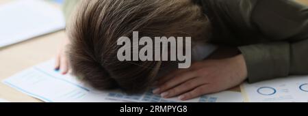A tired young woman in the office sleeps on the table Stock Photo